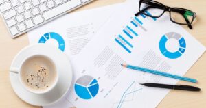 デスクの上のコーヒー紙の書類、パソコン、メガネ