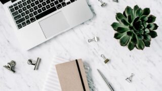 白いデスクの上のパソコンと観葉植物