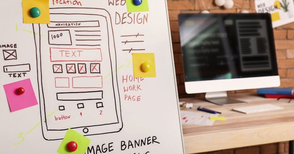 ホームぺージデザイン案が書かれたボードどパソコン