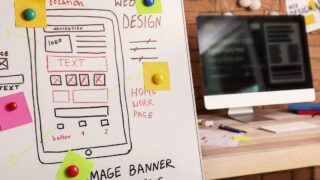 ホームぺージデザイン案が書かれたボードどパソコン