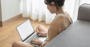ソファの前でパソコン作業を行う女性