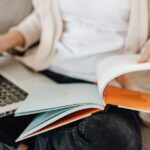 パソコンと本を見ながら作業を行う女性