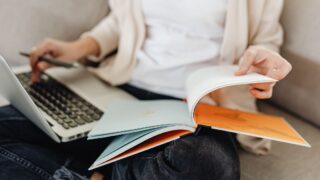 パソコンと本を見ながら作業を行う女性